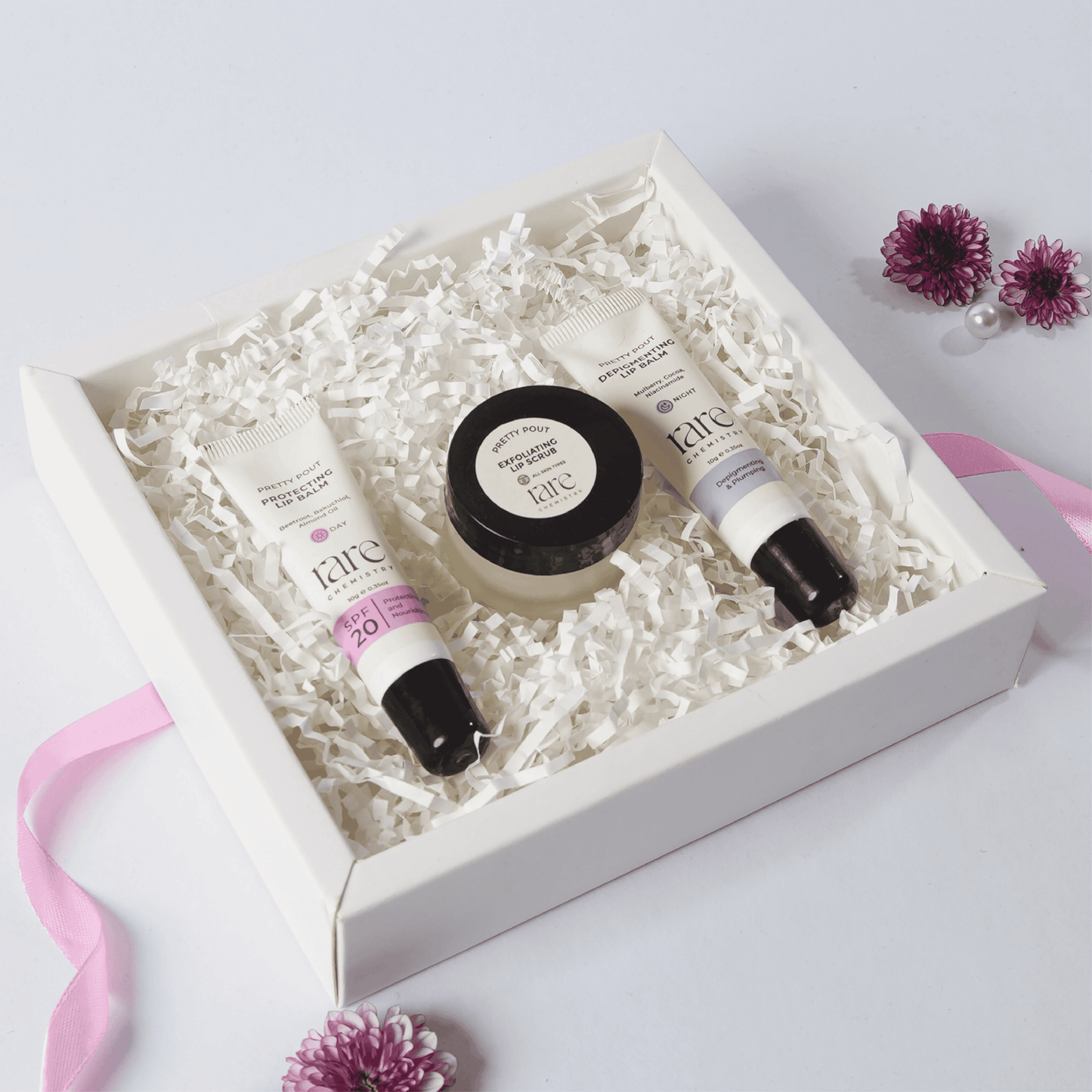 Set of skincare products in a white box with flowers on a light background