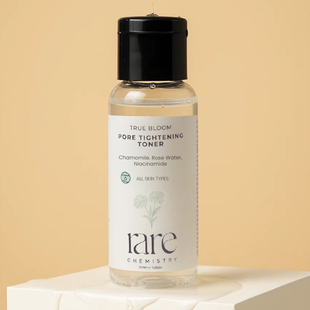 Bottle of True Bloom Pore Tightening Toner by rare chemistry on a beige background